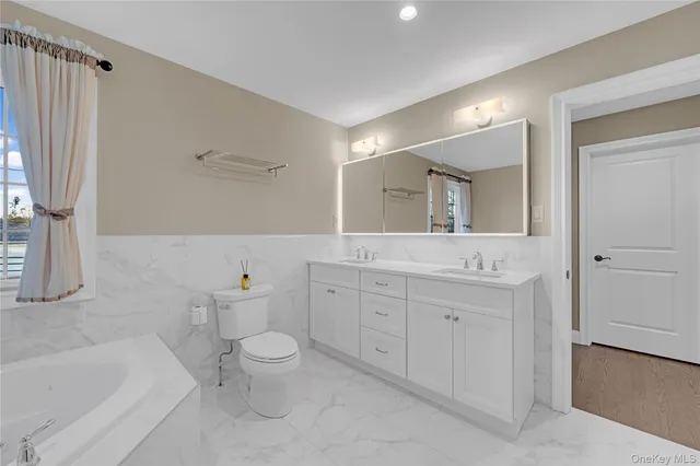 a spacious bathroom with a granite countertop sink a toilet and a bathtub