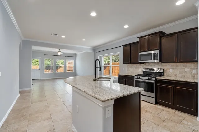 a kitchen with stainless steel appliances granite countertop a stove top oven a sink dishwasher a dining table and chairs with wooden floor