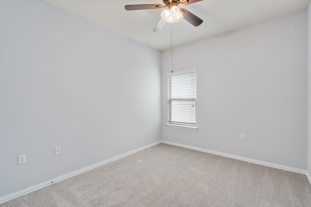 5704 Arbor Hill Lane Austin, TX 78747 - Photo 19 of 32 an empty room with a chandelier fan and windows