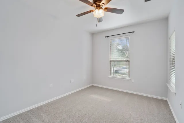 an empty room with a ceiling fan and a window