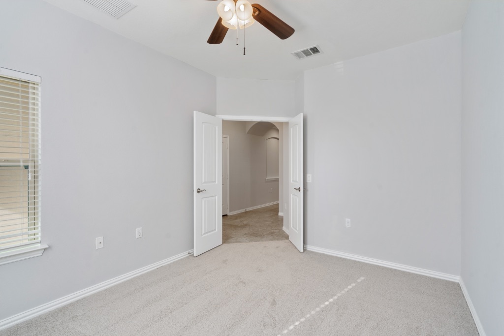 5704 Arbor Hill Lane Austin, TX 78747 - Photo 22 of 32 an empty room with a ceiling fan and a window