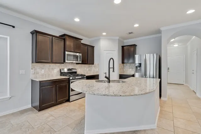 a kitchen with stainless steel appliances granite countertop a stove a sink a microwave and a refrigerator