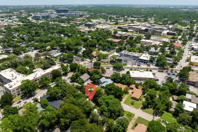 an aerial view of residential houses with outdoor space and trees