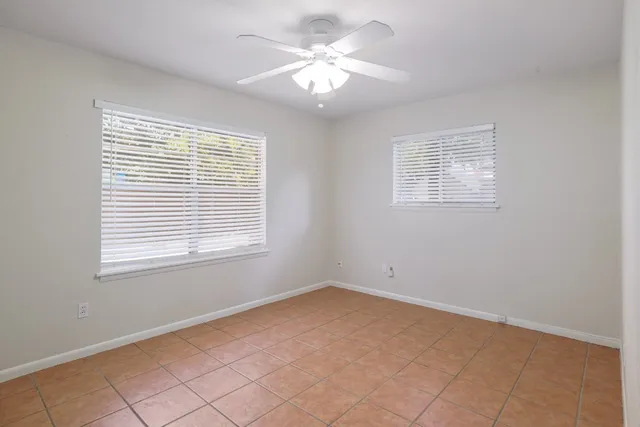 an empty room with windows and chandelier fan