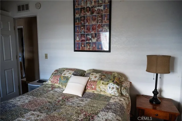 a bedroom with a bed and a lamp on dresser