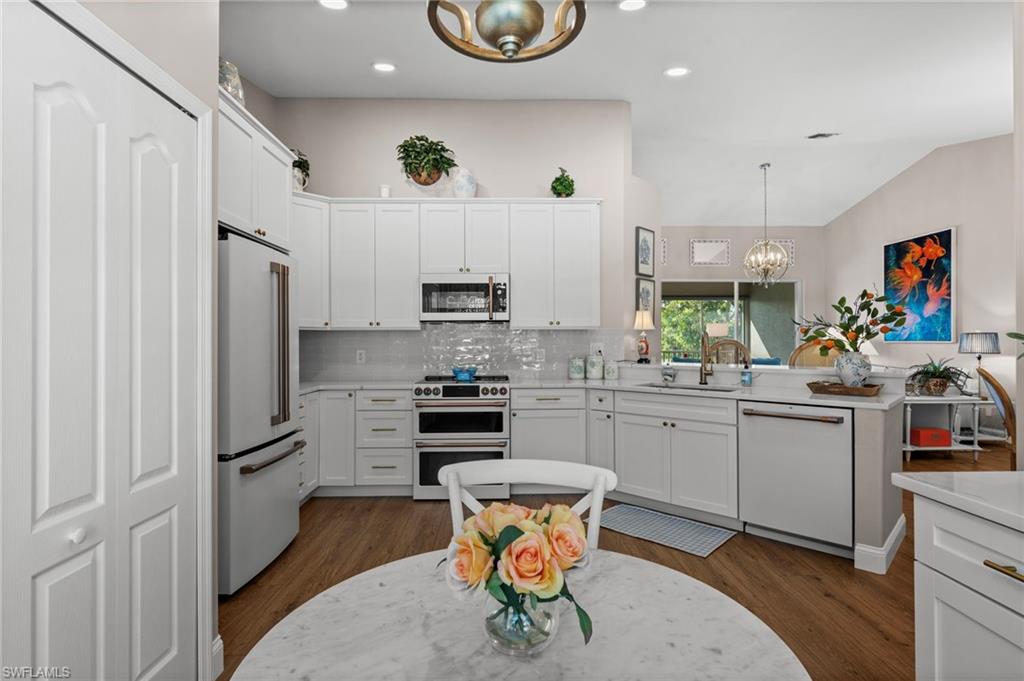 9331 Spring Run Boulevard, Unit 3005 Estero, FL 34135 - Photo 6 of 48 Kitchen featuring white cabinetry, stainless steel appliances, wood-finish flooring, and a subway tile backsplash