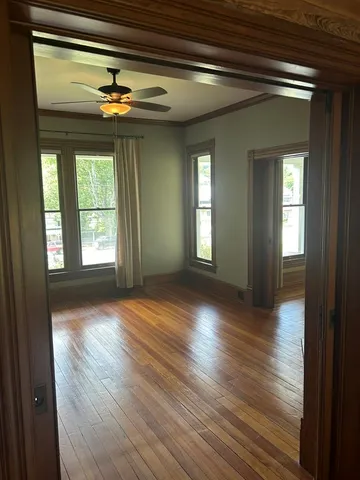 a view of an empty room with wooden floor and a window