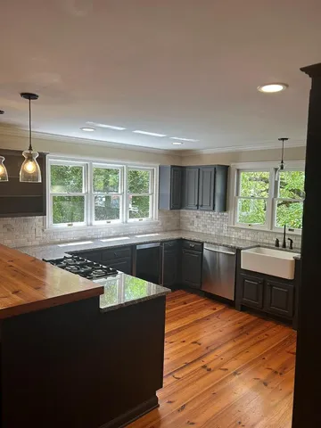 a kitchen with stainless steel appliances granite countertop a stove a sink and a microwave