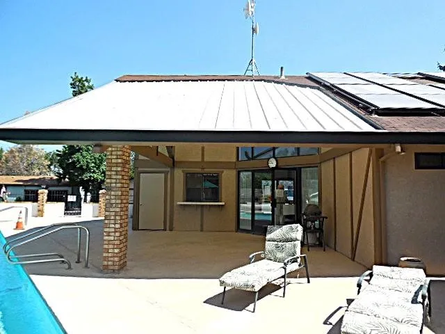 a view of a patio with table and chairs under an umbrella with a barbeque