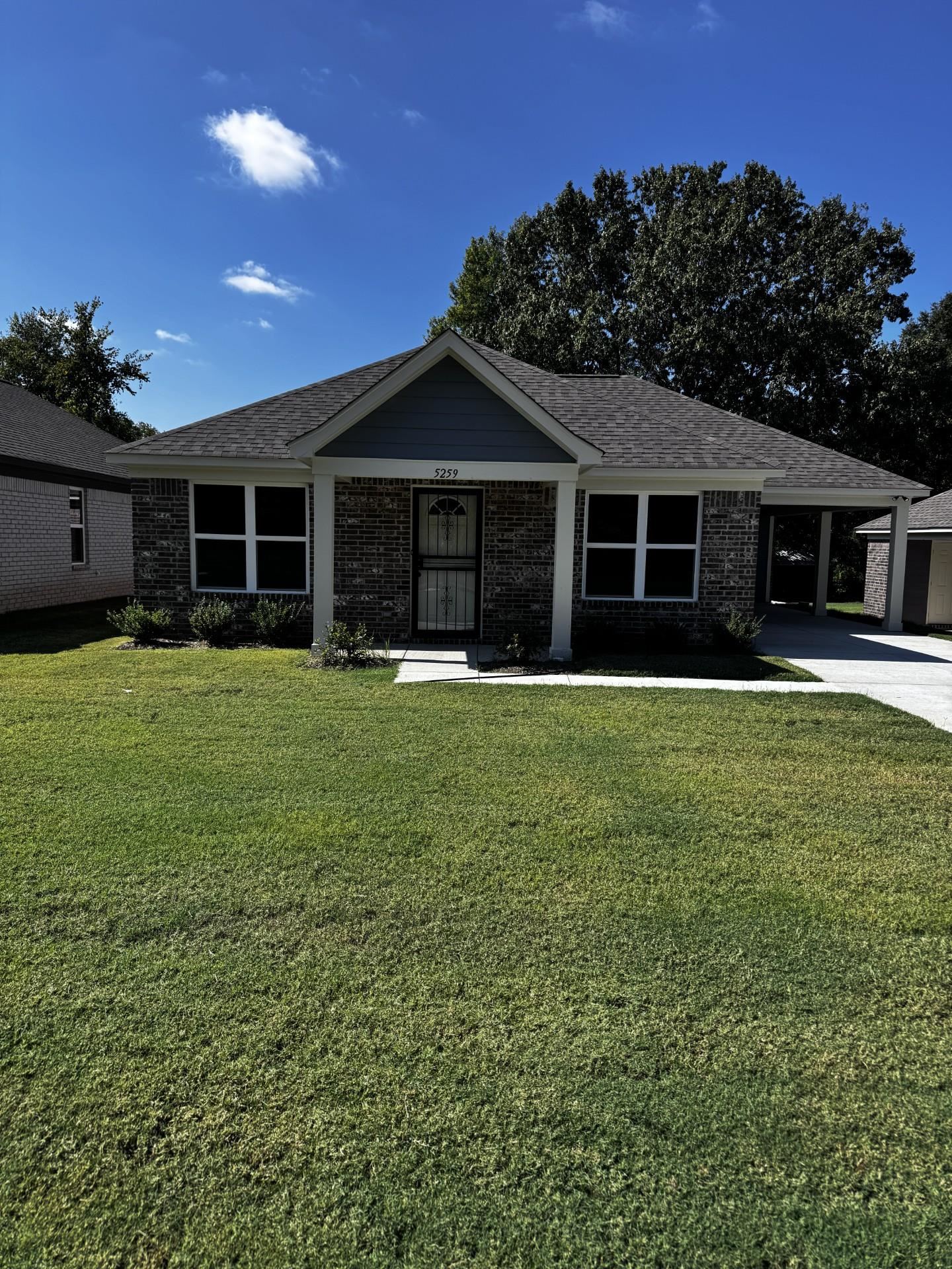 Ranch-style home featuring a front lawn, a carport, and roof with shingles