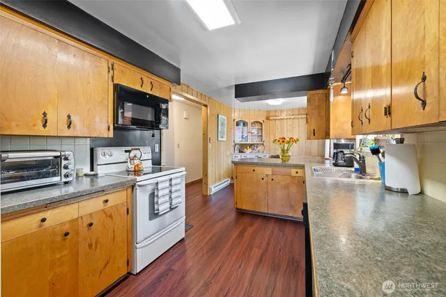 a kitchen with stainless steel appliances a sink a stove a refrigerator cabinets and a dining table
