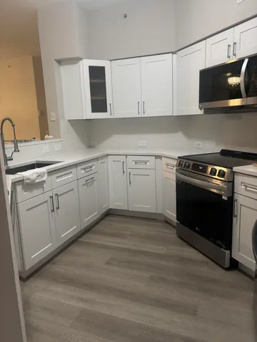 a kitchen with stainless steel appliances granite countertop a stove a sink and white cabinets