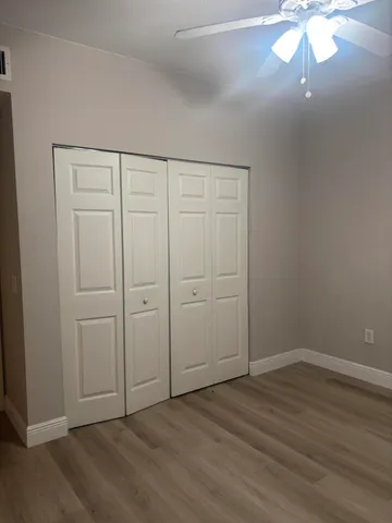 an empty room with wooden floor closet and windows