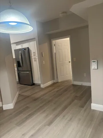 an empty room with wooden floor and a hallway