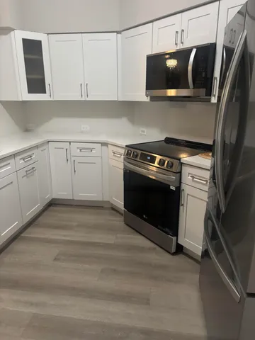 a kitchen with white cabinets and stainless steel appliances
