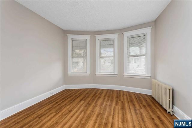 20 Dankoff Avenue, Unit 1 Wallington, NJ 07057 - Photo 11 of 15 an empty room with wooden floor and windows
