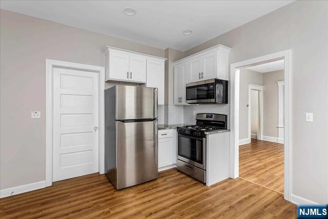 20 Dankoff Avenue, Unit 1 Wallington, NJ 07057 - Photo 5 of 15 a kitchen with a refrigerator stove and wooden cabinets