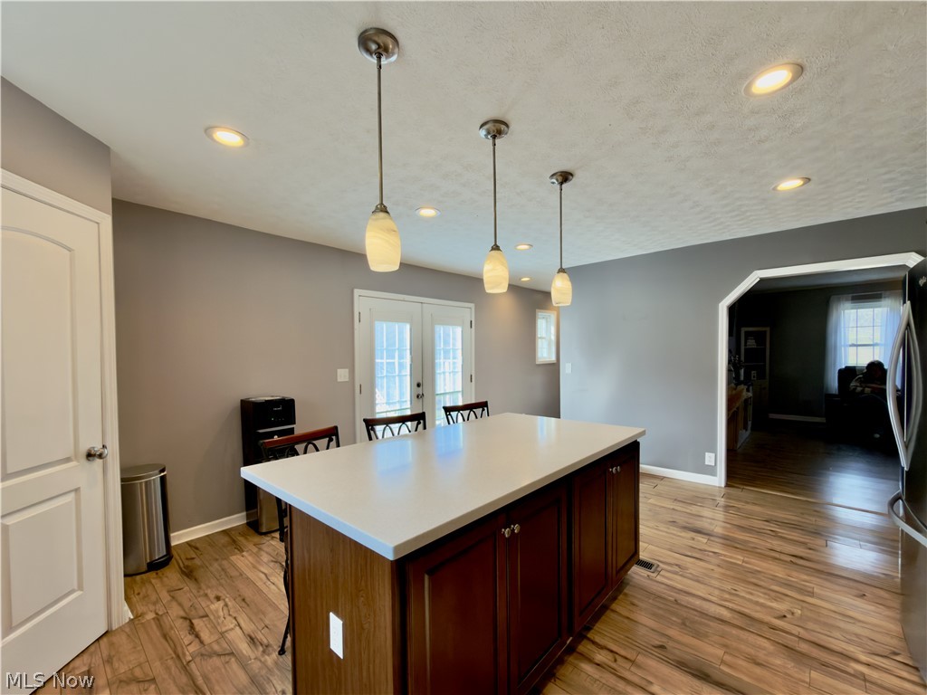 17377 Murphy Road Amesville, OH 45711 - Photo 14 of 43 Kitchen featuring a breakfast bar area, decorative light fixtures, arched walkways, a kitchen island, and a textured ceiling