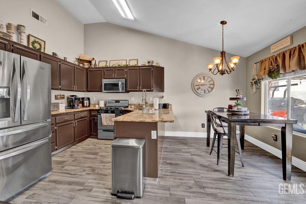 Undisclosed Address Bakersfield, CA 93307 - Photo 9 of 30 a kitchen with kitchen island granite countertop a stove top oven a sink dishwasher a dining table and chairs a refrigerator with wooden floor