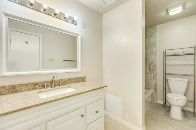 a bathroom with a granite countertop sink a toilet and a mirror