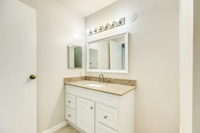a bathroom with a granite countertop sink and a mirror