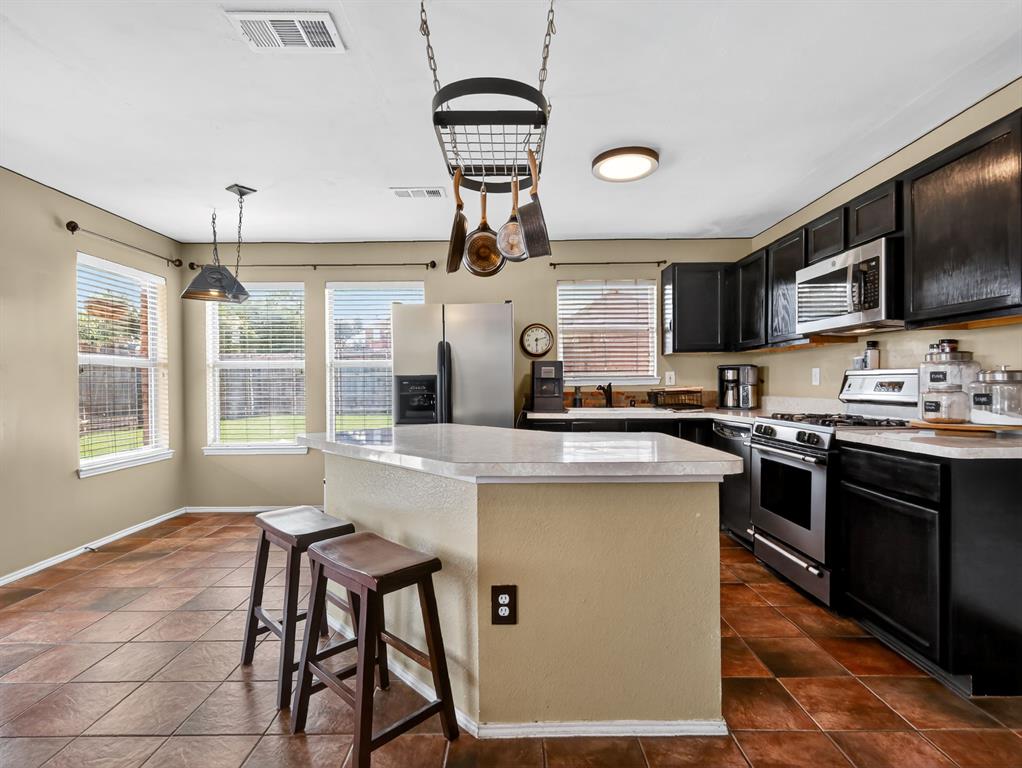 2052 Diamond Ridge Drive Carrollton, TX 75010 - Photo 34 of 40 a kitchen with stainless steel appliances granite countertop a stove top oven a sink dishwasher a dining table and chairs with wooden floor