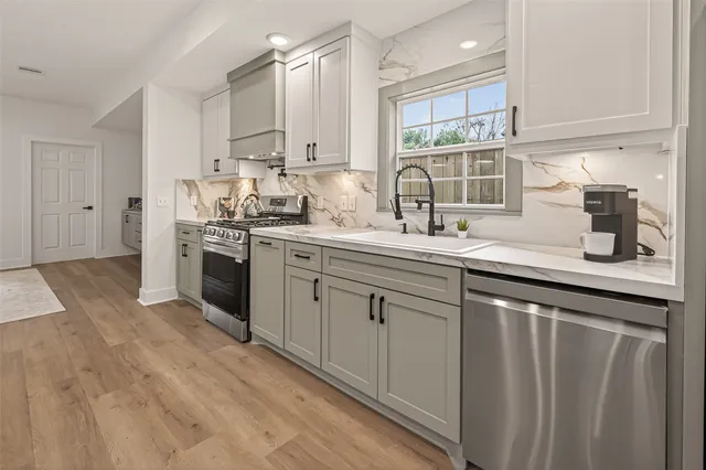 a kitchen with stainless steel appliances granite countertop a sink a stove and cabinets