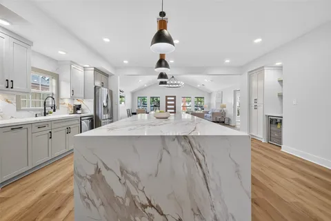 a kitchen with stainless steel appliances granite countertop a stove a sink dishwasher and a dining table with wooden floor