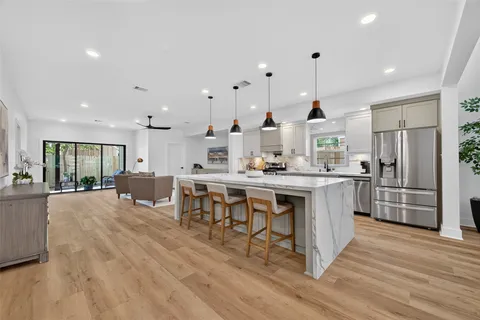 a kitchen with stainless steel appliances kitchen island granite countertop a stove a refrigerator a oven a sink with a dining table and chairs