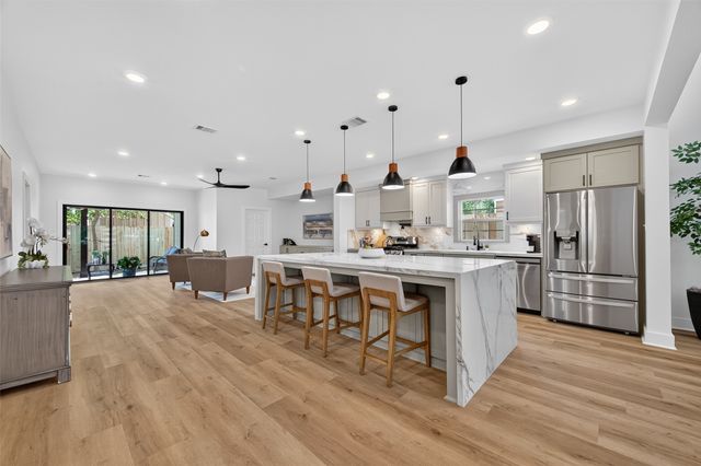 a kitchen with stainless steel appliances kitchen island granite countertop a stove a refrigerator a oven a sink with a dining table and chairs