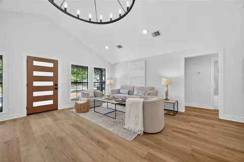a living room with couches and kitchen view with wooden floor