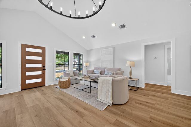 a living room with couches and kitchen view with wooden floor