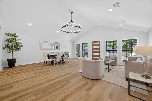 a living room with furniture and potted plants with wooden floor