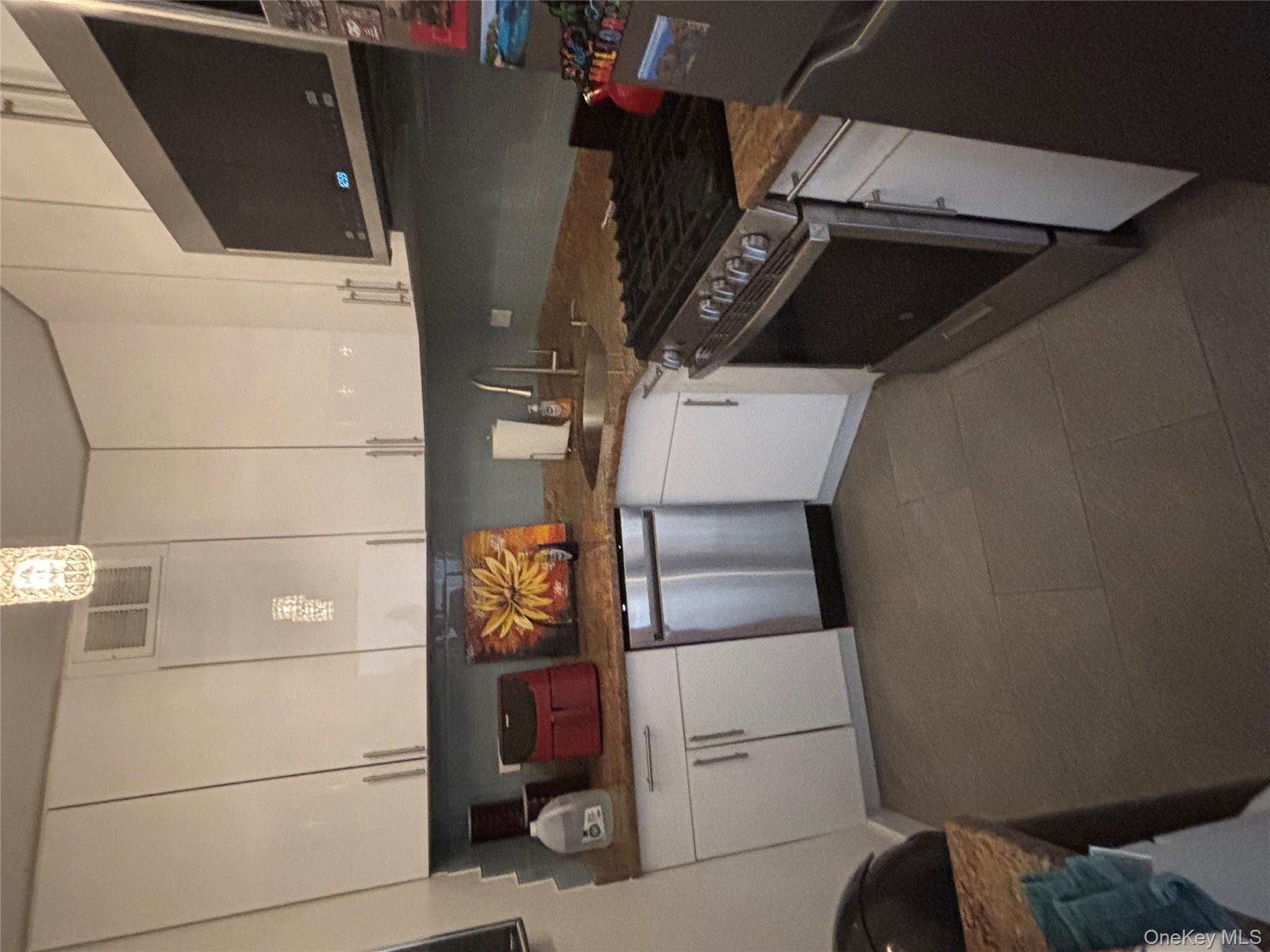 102-10 66th Road, Unit 14C Queens, NY 11375 - Photo 3 of 10 Kitchen featuring white cabinets, stainless steel microwave, range, dishwasher, and dark stone counters