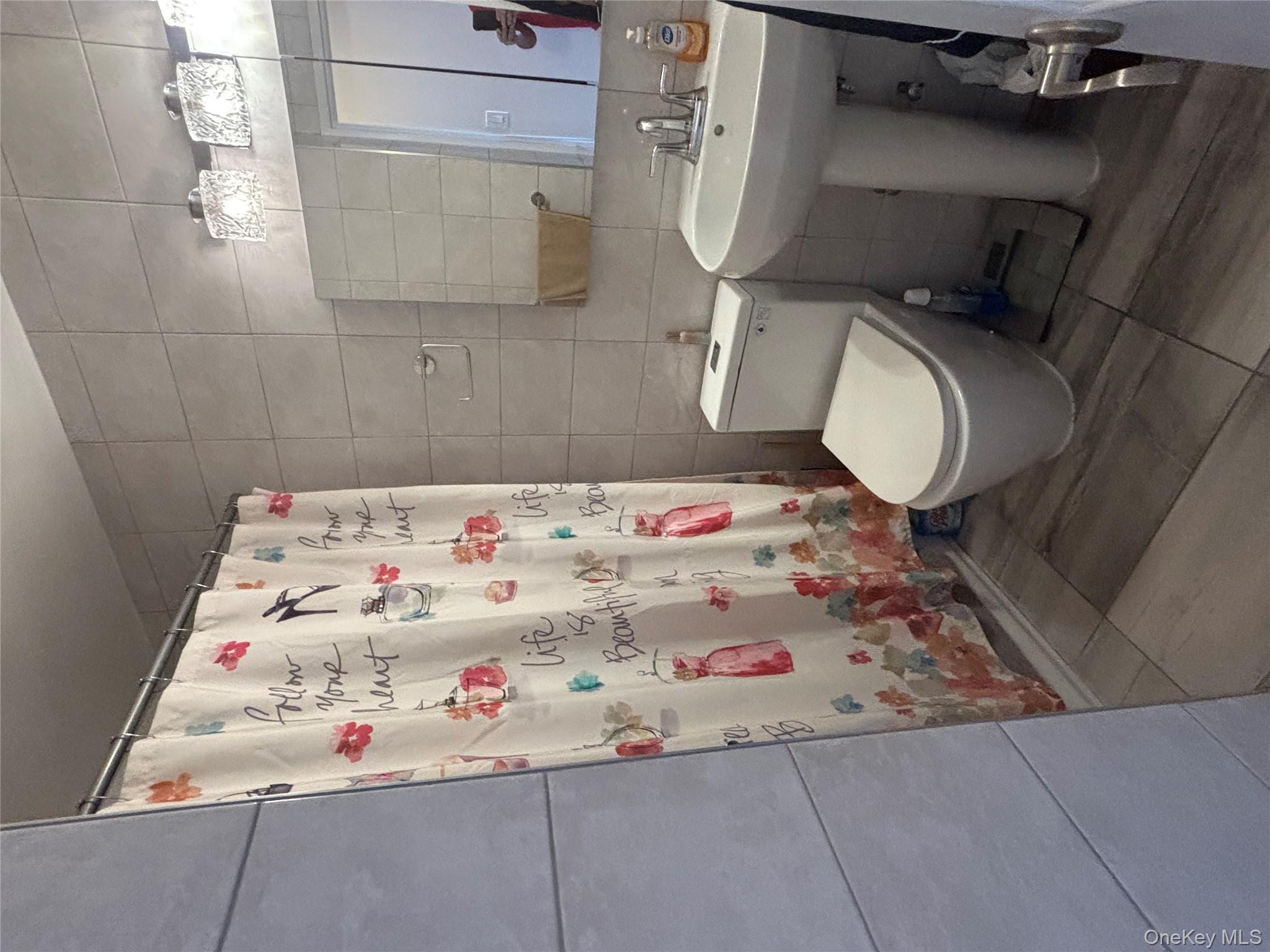 102-10 66th Road, Unit 14C Queens, NY 11375 - Photo 4 of 10 Bathroom with tile walls and curtained shower