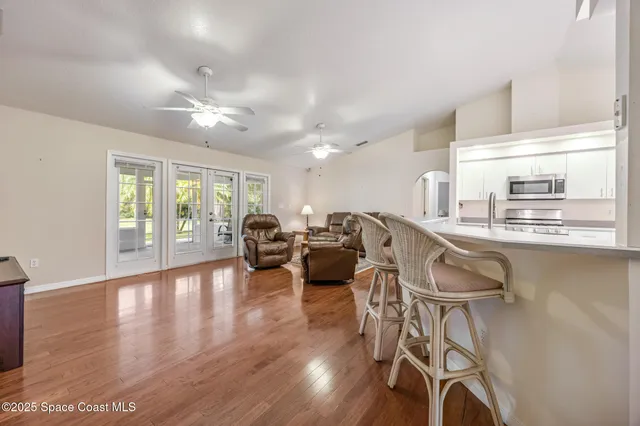 a living room with furniture a large window and wooden floor