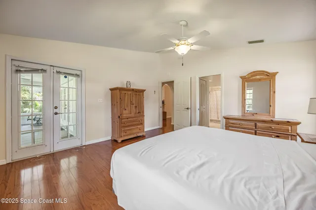 a bedroom with a large bed and chandelier fan
