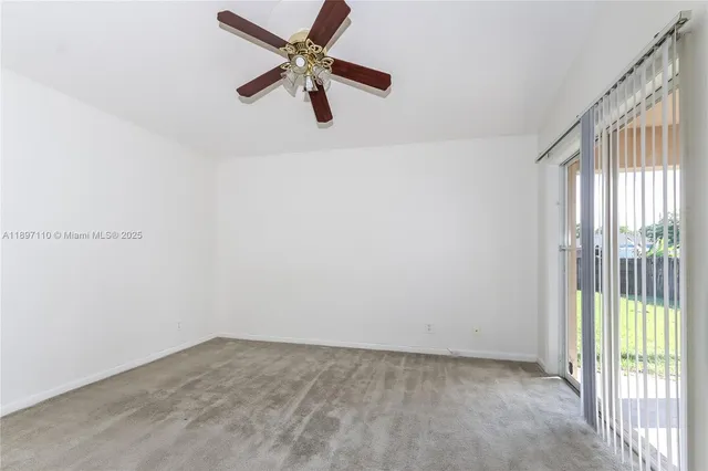 an empty room with a ceiling fan and windows