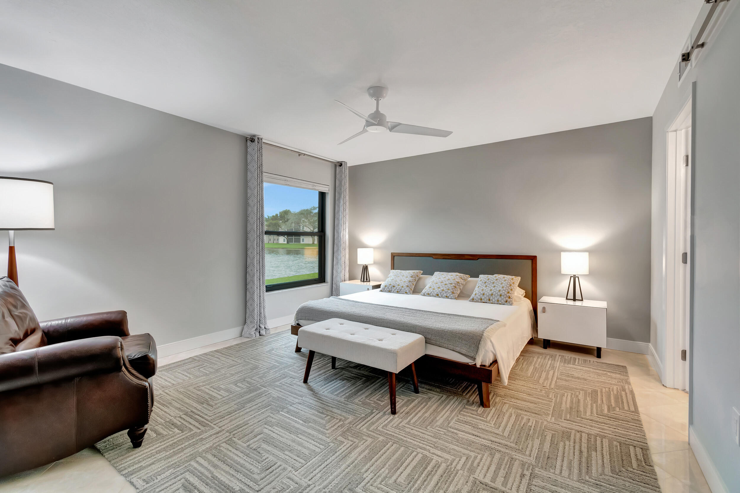 6269 Pointe Regal Circle, Unit 102 Delray Beach, FL 33484 - Photo 20 of 51 a spacious bedroom with a bed a couch and a window