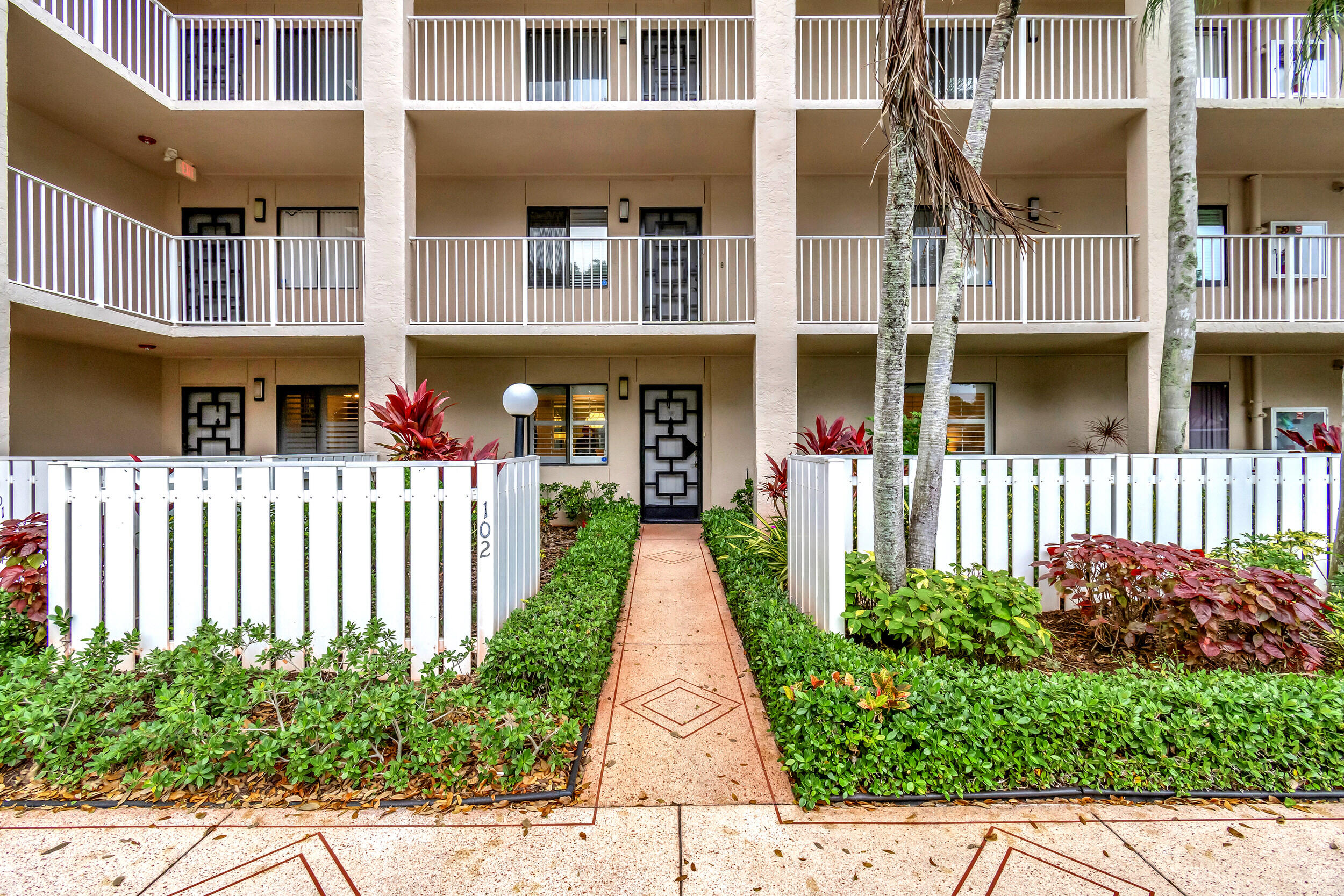 6269 Pointe Regal Circle, Unit 102 Delray Beach, FL 33484 - Photo 3 of 51 a view of a brick house with potted plants and a small yard