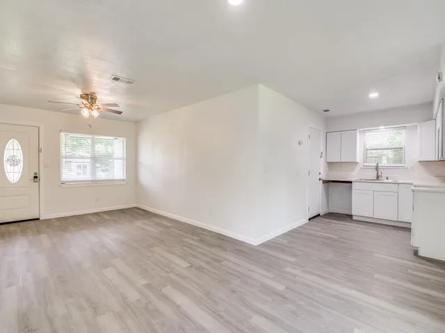 a view of an empty room with window and wooden floor