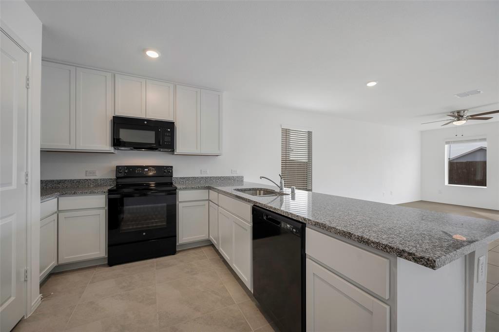 209 Boxberry Way Princeton, TX 75407 - Photo 4 of 34 a kitchen with a sink and a stove top oven with wooden floor
