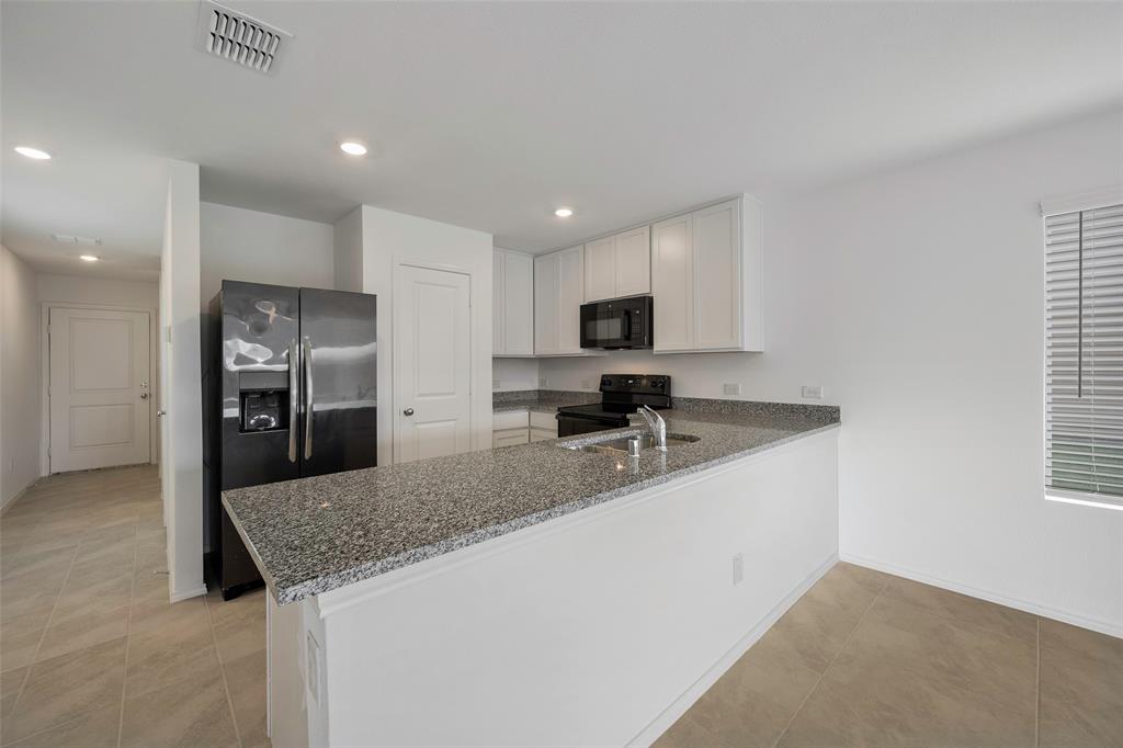 209 Boxberry Way Princeton, TX 75407 - Photo 5 of 34 a kitchen with stainless steel appliances granite countertop a sink refrigerator and microwave