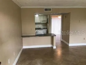 a view of a refrigerator in kitchen and an empty room