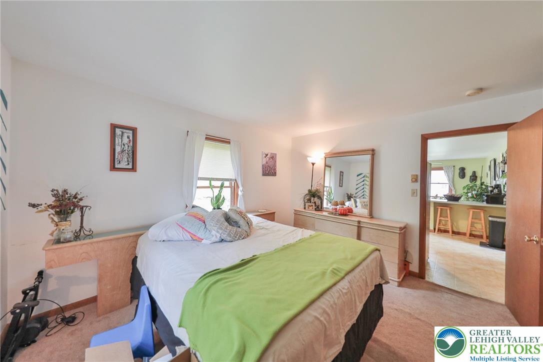 4608 Pine Ridge Drive West Bushkill, PA 18324 - Photo 39 of 62 A comfortable bedroom with a plush bed offers direct sightlines to the adjacent kitchen.