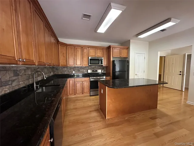 a large kitchen with stainless steel appliances granite countertop a stove a sink dishwasher and a refrigerator with wooden floor