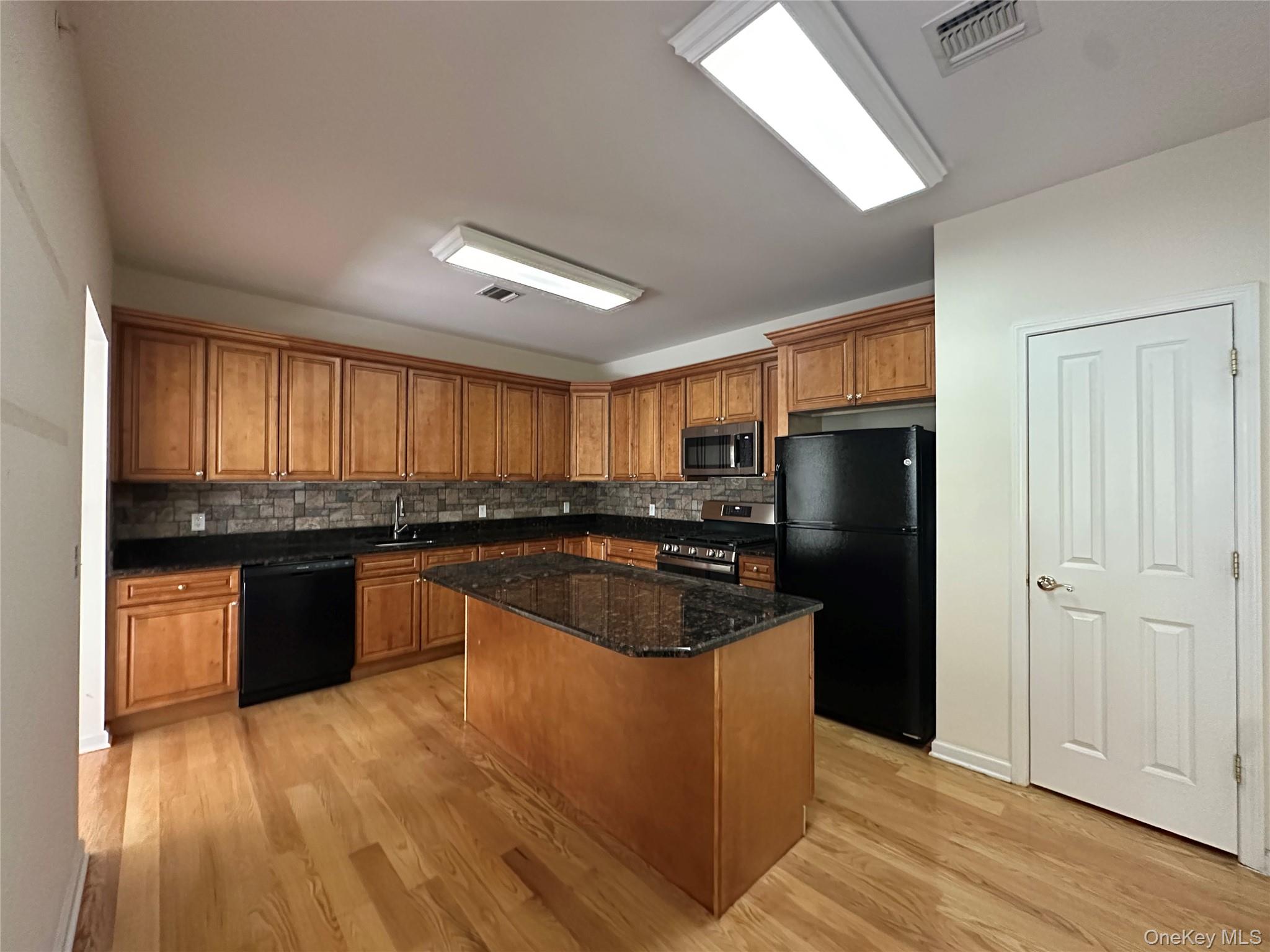 75 Quaker Avenue, Unit 315 Cornwall, NY 12518 - Photo 12 of 48 a kitchen with stainless steel appliances granite countertop a refrigerator a sink dishwasher a stove and white countertops with wooden floor