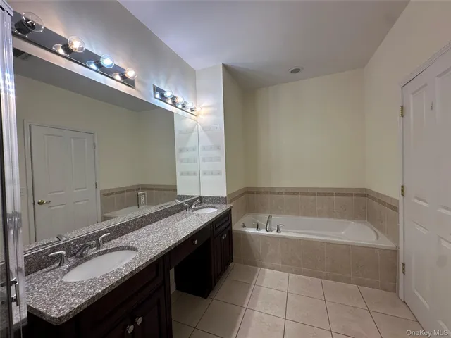 a spacious bathroom with a granite countertop tub a double vanity sink and a mirror