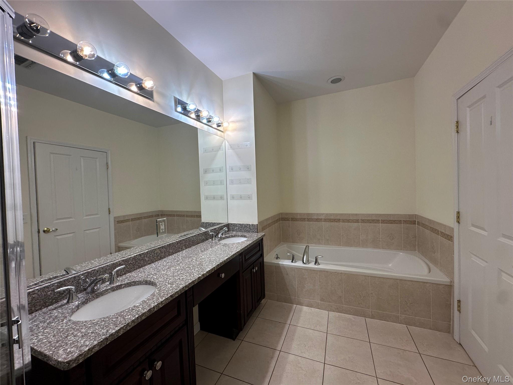 75 Quaker Avenue, Unit 315 Cornwall, NY 12518 - Photo 34 of 48 a spacious bathroom with a granite countertop tub a double vanity sink and a mirror