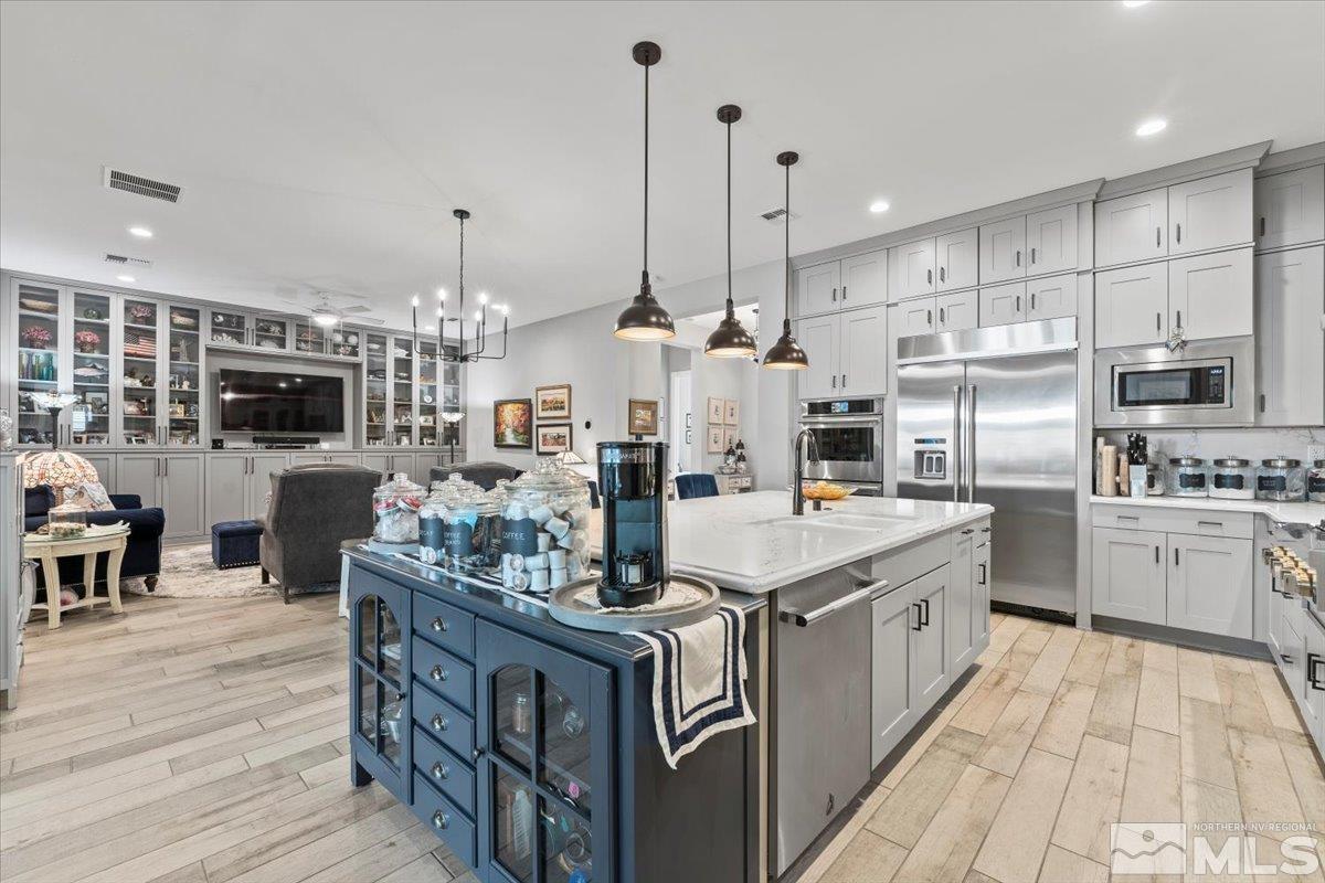 a kitchen with stainless steel appliances kitchen island granite countertop a table chairs stove and cabinets